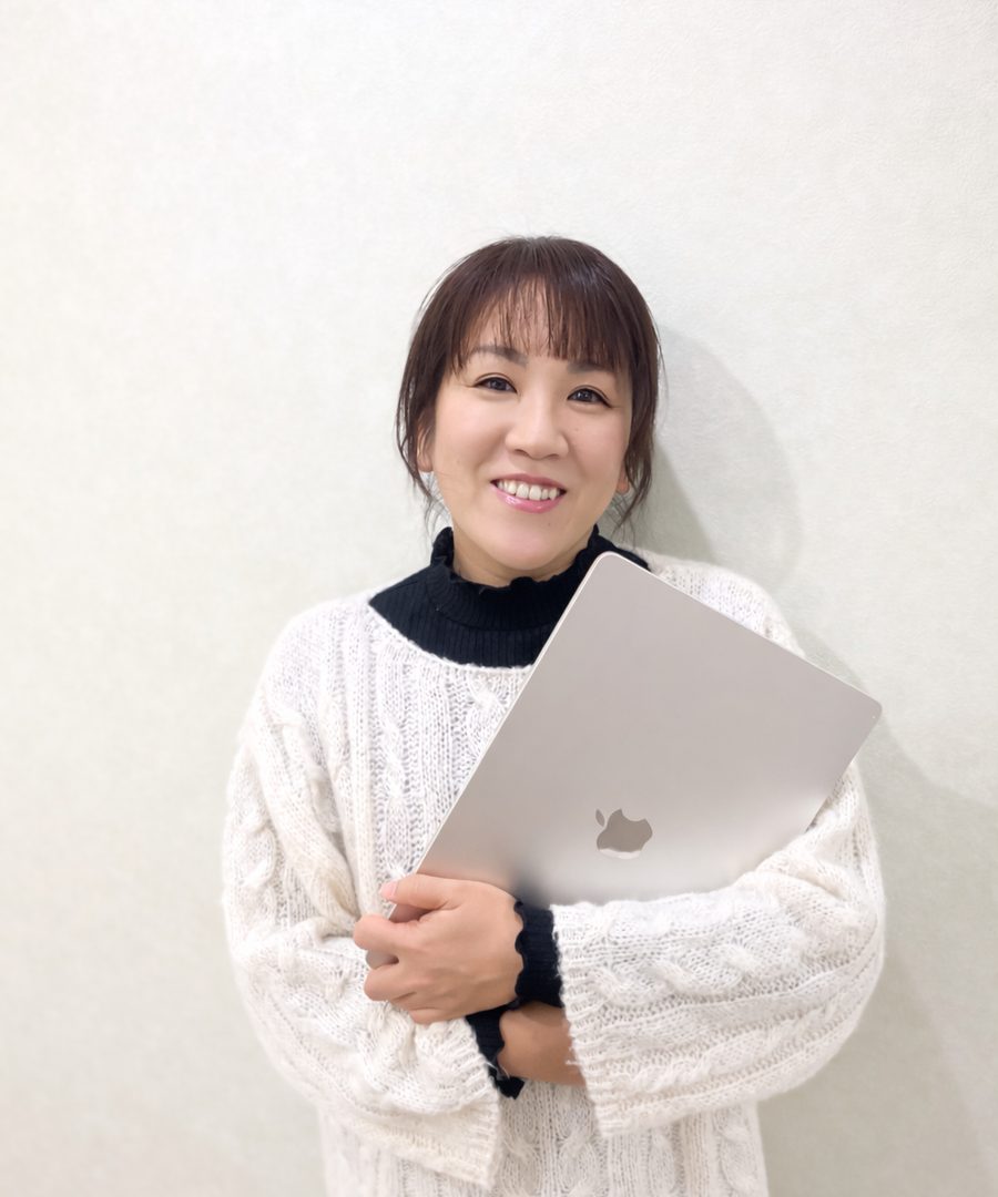 ノートパソコンを抱えて微笑むプロフィール写真